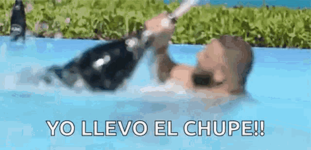 a man is holding a bottle of champagne in a pool .