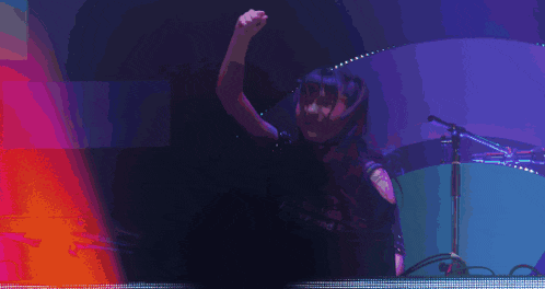 a woman is dancing in front of a microphone with a purple background