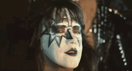 a close up of a woman with makeup on her face pointing her finger .