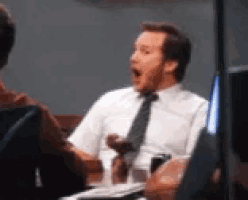 a man in a white shirt and tie is yawning while sitting at a table with other people .