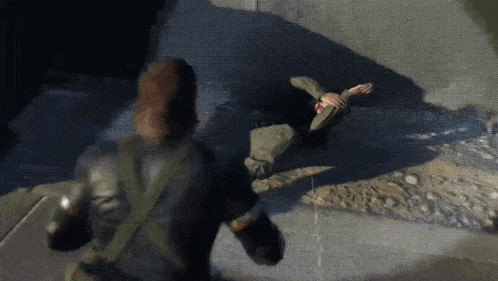 a man in a military uniform is standing next to another man laying on the ground