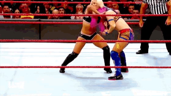 two women are wrestling in a wrestling ring .