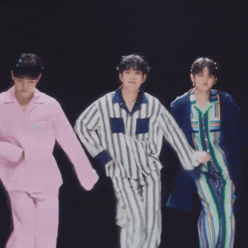 three men in pajamas are dancing in a dark room