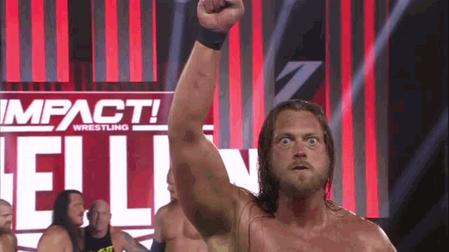 a wrestler with his fist in the air in front of a banner that says impact wrestling