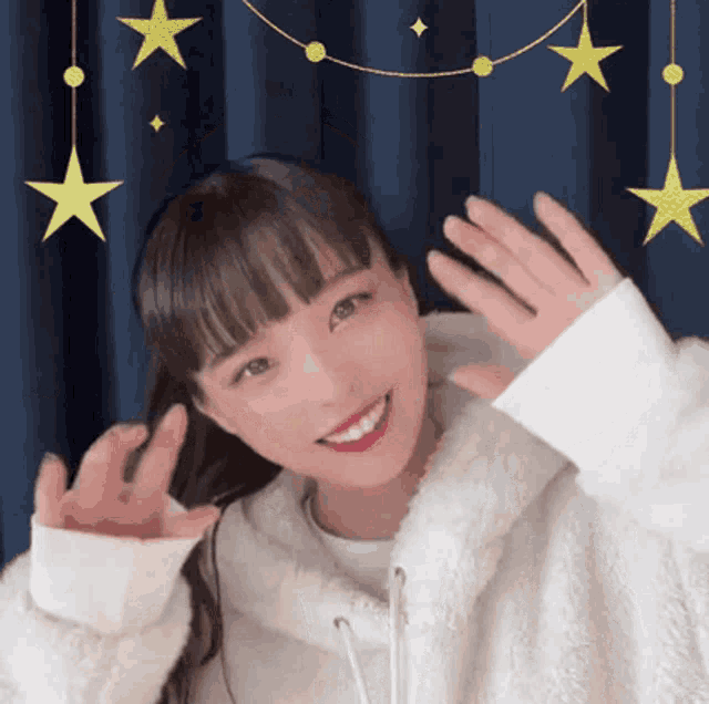 a woman wearing a white hoodie is smiling and waving