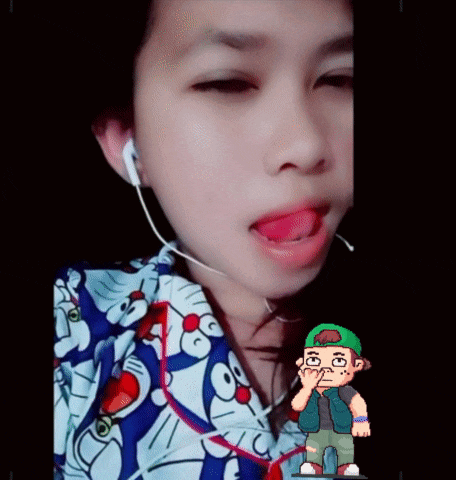 a girl wearing a doraemon shirt has her tongue out and a cartoon character behind her