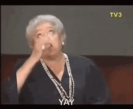 a woman wearing a pearl necklace and earrings is making a funny face and saying yay .