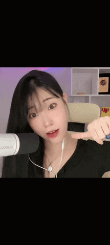 a young woman wearing headphones and a black shirt is giving a thumbs up .