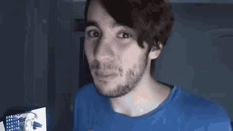 a man with a beard wearing a blue shirt is looking at the camera