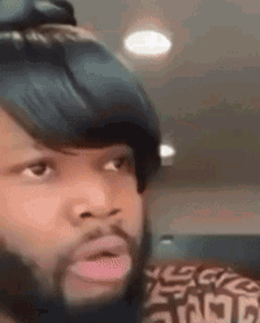 a man with a beard and black hair is making a funny face while looking at the camera .