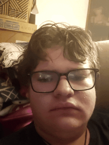 a person wearing glasses is sitting in front of a box that says avon on it