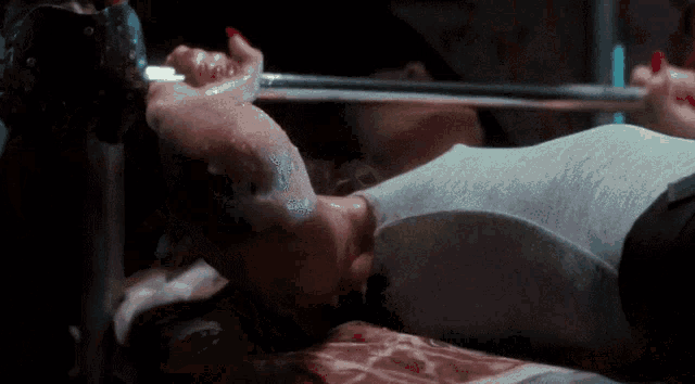 a woman laying on a bed with a sword in her mouth