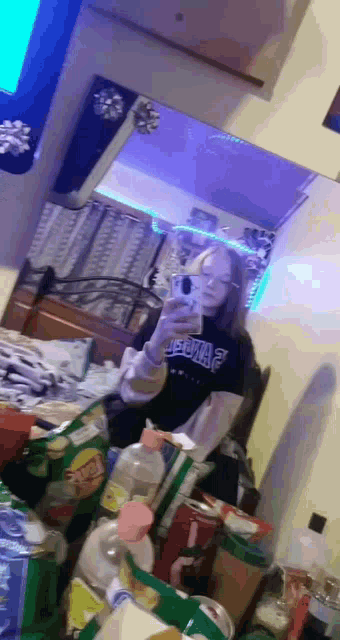 a girl is taking a selfie in front of a mirror in her bedroom .