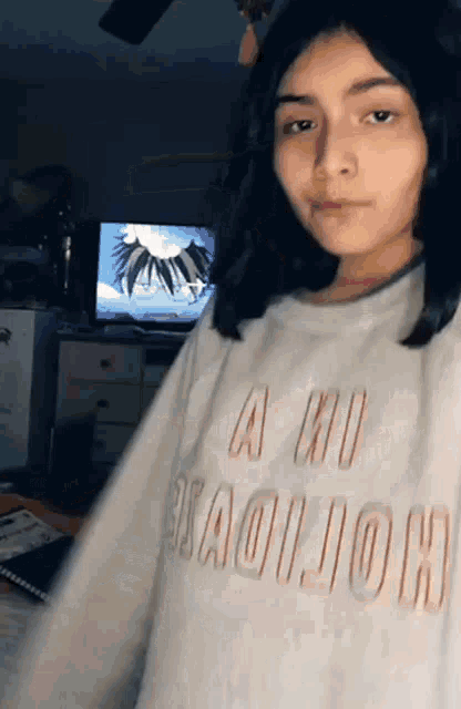a young girl wearing a white shirt that says a no is standing in front of a television