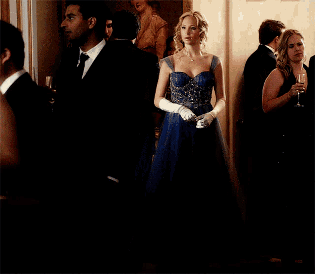 a woman in a blue dress is standing in a crowd