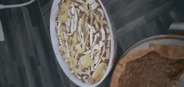 a casserole dish filled with vegetables and cheese sits on a wooden table
