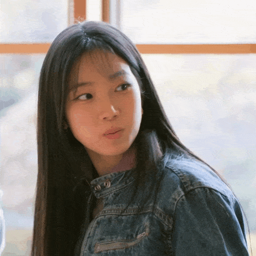 a girl with long hair wearing a denim jacket
