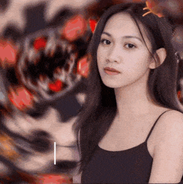 a woman in a black tank top stands in front of a blurred image of a monster