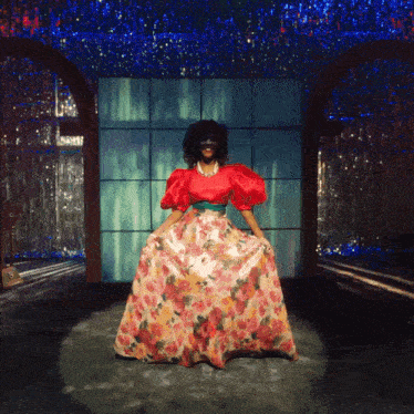 a woman wearing a red top and floral skirt
