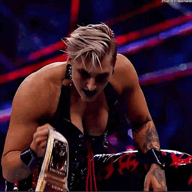 a woman in a black top is holding a championship belt .