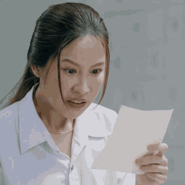 a woman in a white shirt holds a piece of paper in her hand