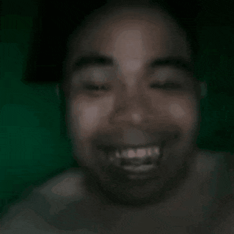 a man with a beard is smiling with his eyes closed in a blurry picture .