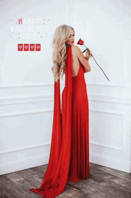 a woman in a red dress is holding a rose in front of a sign that says happy valentines day