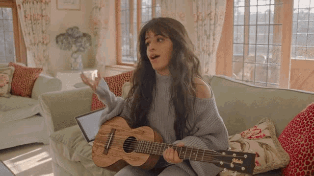 a woman is sitting on a couch playing a guitar that says jackson