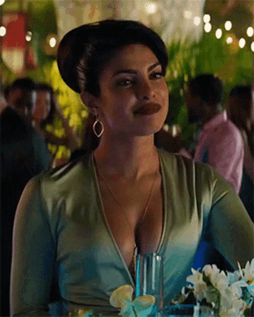 a woman in a green top with a plunging neckline is sitting at a table .