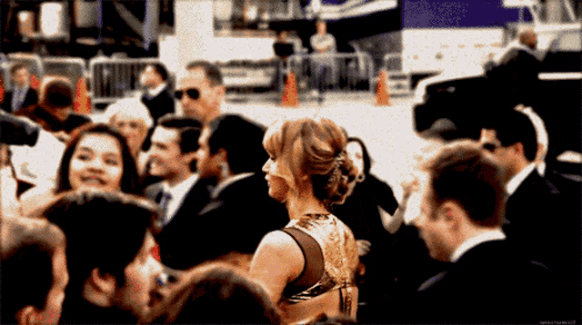 a woman in a gold dress is surrounded by a crowd