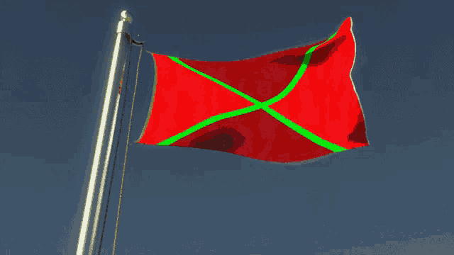 a red flag with a green cross is flying in the wind