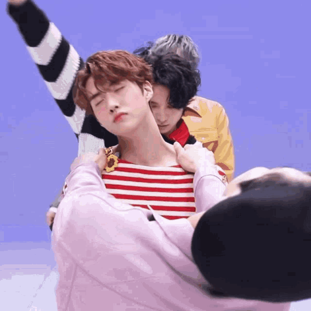 a man in a striped shirt is being held by another man in a pink shirt