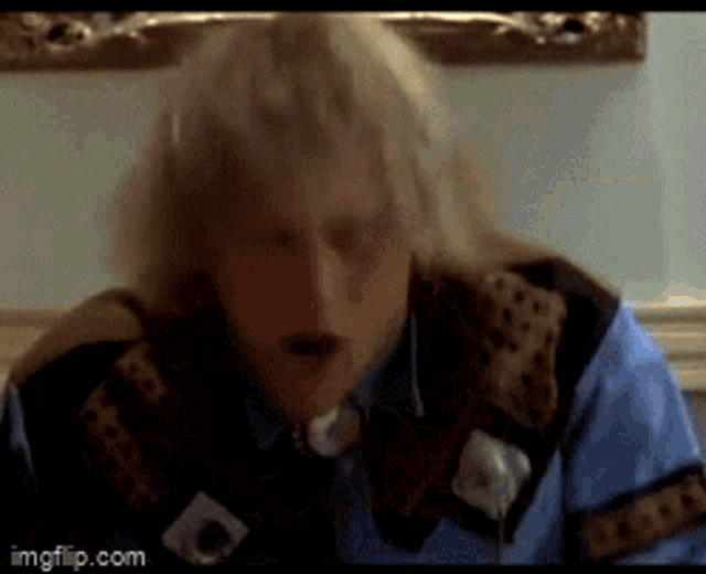 a man with blonde hair is wearing a blue shirt and a brown jacket