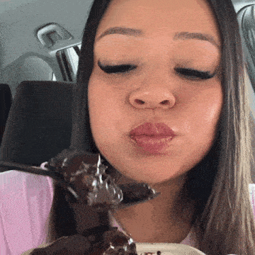 a woman blowing a kiss while holding a piece of chocolate cake
