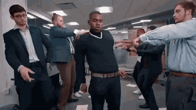 a group of men are standing in a room dancing together .