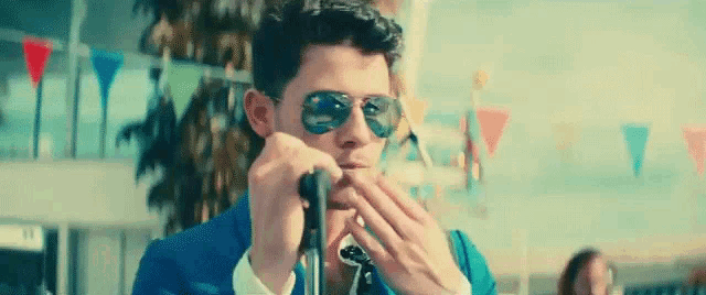 a man in a suit and sunglasses is playing a harmonica .