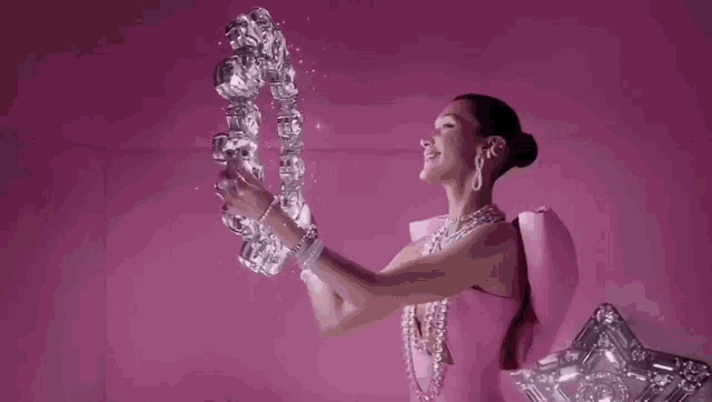 a woman in a pink dress is holding a crystal sculpture