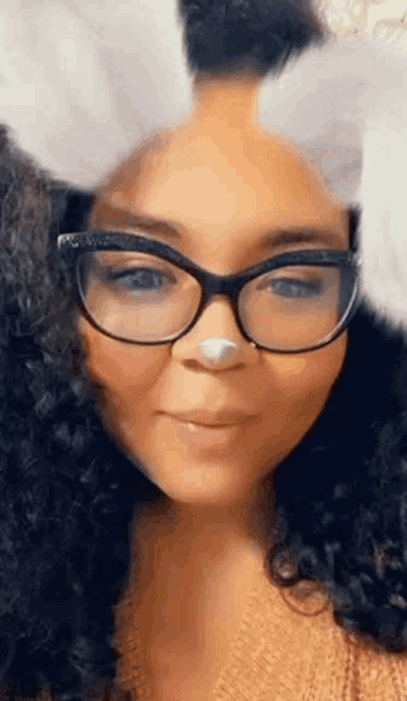 a woman wearing glasses and bunny ears is smiling