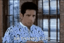 a man in a hospital gown is standing in front of a window and saying `` ah thanks cuz ! ''