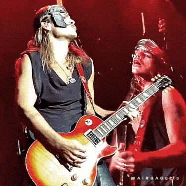two men are playing guitars on a stage with the words " airbags " written on the bottom