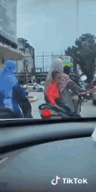 a woman is riding a scooter with a child on the back .