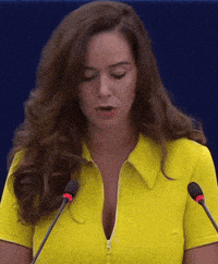 a woman in a yellow shirt is standing in front of two microphones