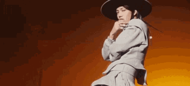 a woman wearing a hat and a sweater is dancing on a stage .