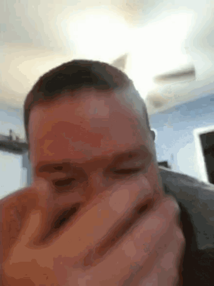 a close up of a man covering his mouth with his hand