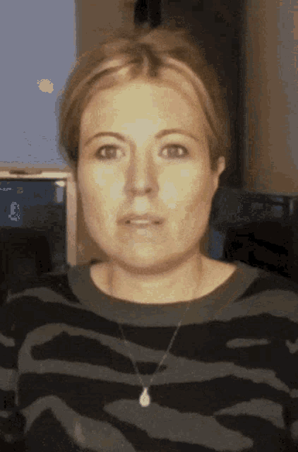 a woman wearing a zebra print sweater and a necklace is making a funny face