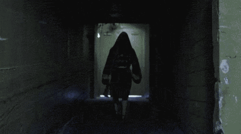 a person is walking down a dark hallway with a light shining on them