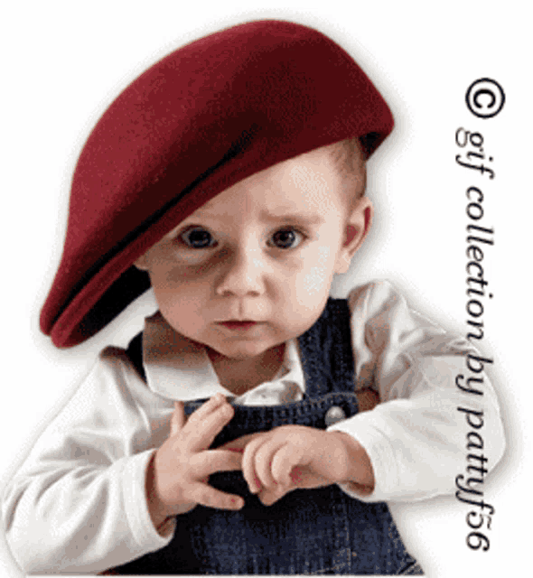 a baby wearing a maroon beret and overalls is making a peace sign