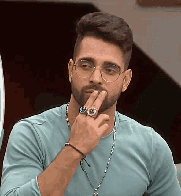 a man with a beard wearing glasses and a ring with the letter j on it