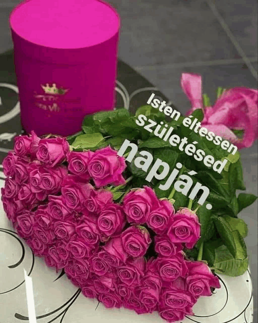 a bunch of pink roses next to a pink box that says isten elessen születésed napjan