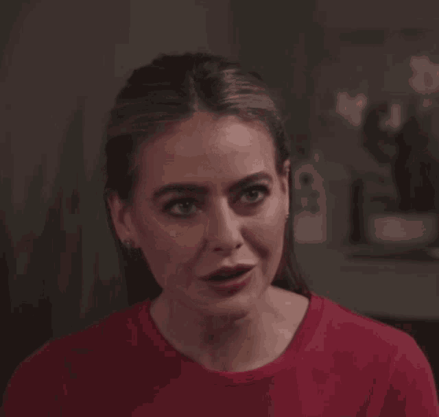 a woman wearing a red shirt is making a face